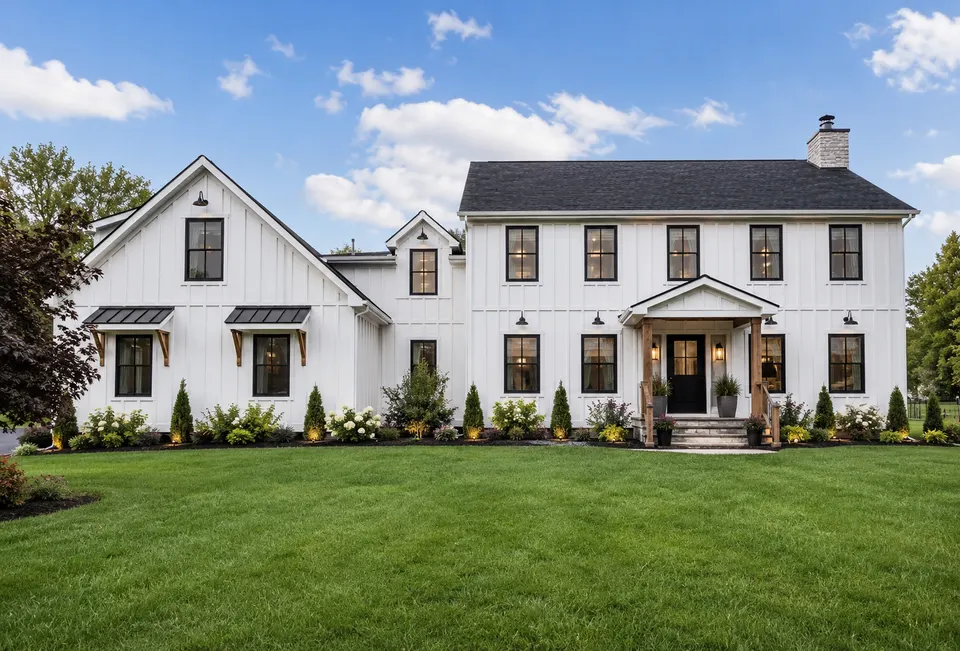 White modern farmhouse with black-trimmed windows and landscaped lawn